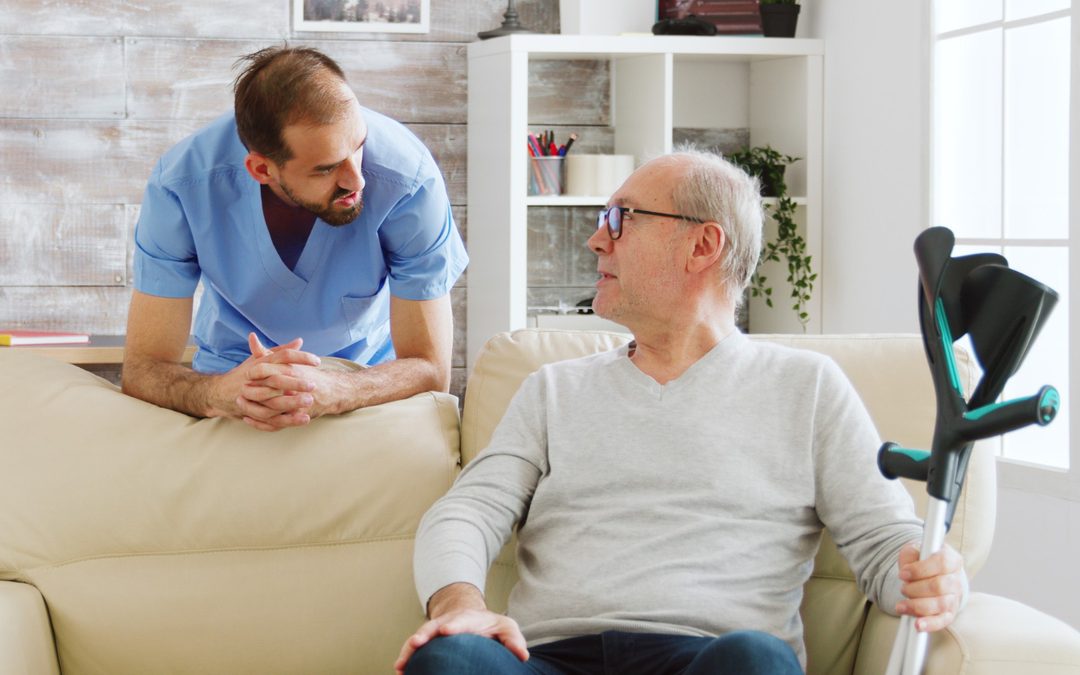 Elderly man and a caregiver having a conversation in a living room.